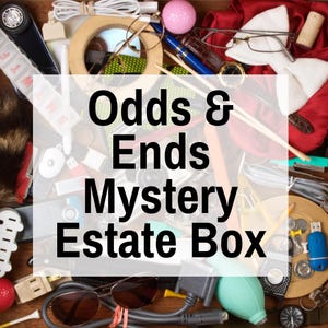 May include: A collection of various items, including a pink golf ball, sunglasses, pens, and a watch, arranged in a wooden box. The text "Odds & Ends Mystery Estate Box" is overlaid on the image.