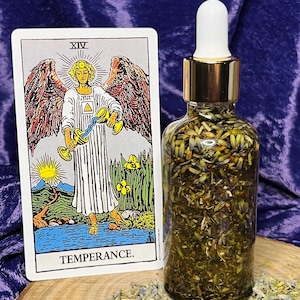 May include: A glass bottle with a gold lid and dropper filled with dried herbs and a tarot card depicting the Temperance card from the Major Arcana. The card shows an angel pouring water from one cup to another.