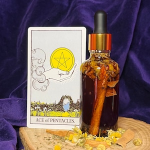 Pode incluir: Uma garrafa de vidro com tampa dourada e conta-gotas cheia de ervas e especiarias. A garrafa está sobre uma superfície de madeira com uma carta de tarô que diz "ACE of PENTACLES."