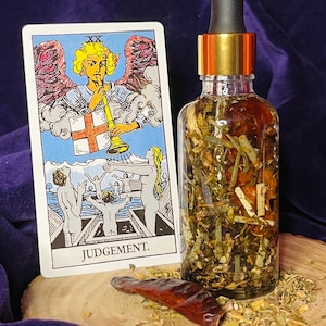 May include: A tarot card depicting an angel playing a trumpet, with the text "JUDGEMENT" at the bottom. A clear glass bottle with a gold lid and a black dropper contains a mixture of herbs and dried fruit. The bottle is resting on a wooden surface.