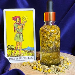 May include: A clear glass bottle with a black dropper and gold accents, filled with yellow liquid and dried flowers, sits next to a tarot card. The card features an illustration of a person holding a star, with the text "PAGE of PENTACLES."