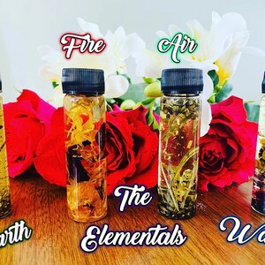 May include: Five small glass bottles with black caps filled with a clear liquid and various dried flowers and herbs. The bottles are labeled "Earth", "Fire", "Air", "Water", and "The Elementals".