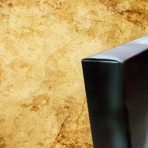 May include: Close-up of the edge of a canvas print with a dark brown background and a blue and green abstract design.