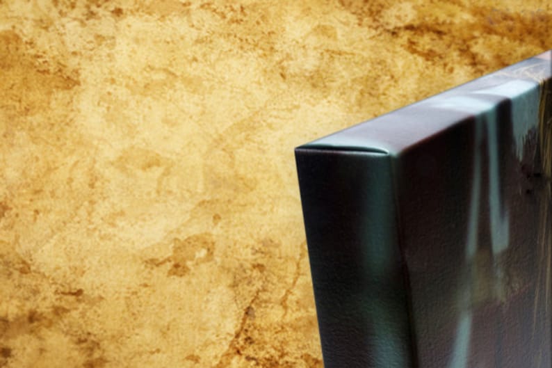 May include: Close-up of the edge of a canvas print with a dark brown background and a blue and green abstract design.