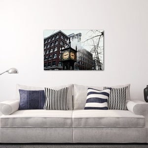May include: A black and white photograph of a clock tower in a city. The clock tower is made of brick and has a large clock face. The clock tower is surrounded by other buildings. The photo is taken from a low angle, looking up at the clock tower.