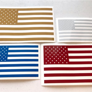 May include: Four American flag decals in different colors: gold, silver, blue, and red. The decals are printed on white paper.