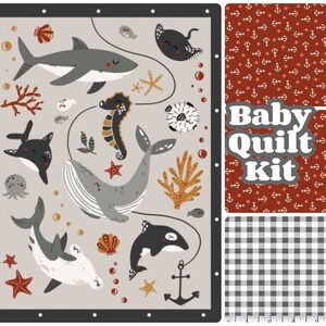 May include: A baby quilt kit featuring a gray and white whale, a gray shark, a seahorse, and an anchor. The kit includes three different fabrics: a red fabric with white anchors and stars, a gray and white gingham fabric, and a gray fabric with a sea life pattern.