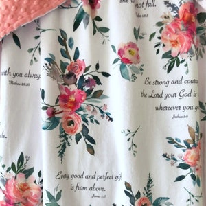 May include: White blanket with a floral pattern featuring pink and peach roses, green leaves, and inspirational quotes from the Bible. The blanket has a soft, textured coral border.