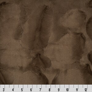 May include: Close-up of a brown faux fur fabric with a soft, plush texture.