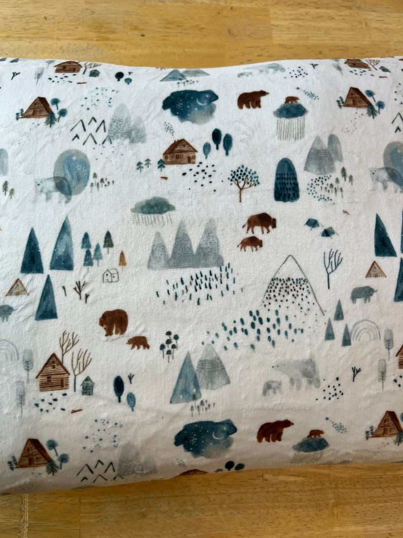 May include: White pillowcase with a woodland pattern featuring bears, mountains, trees, and cabins. The pattern is in shades of blue, brown, and grey.