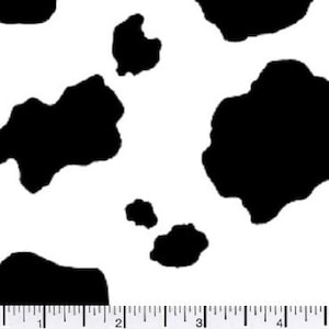 May include: A white background with large, irregular black spots, resembling a cowhide pattern. A ruler with inch markings is visible along the bottom edge, providing a scale for the pattern's size.