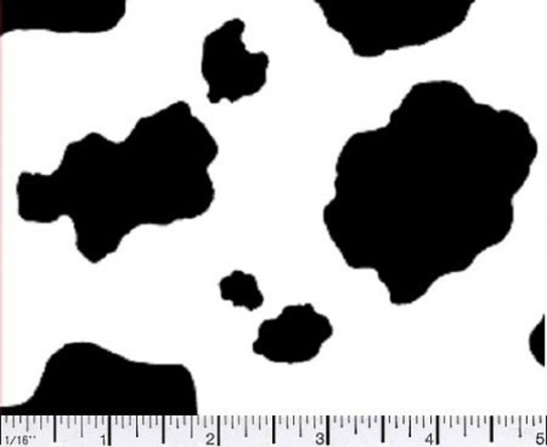May include: A white background with large, irregular black spots, resembling a cowhide pattern. A ruler with inch markings is visible along the bottom edge, providing a scale for the pattern's size.