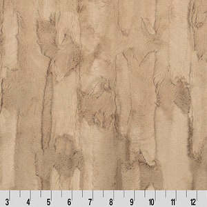 May include: A close-up of a beige faux fur fabric with a vertical striped pattern. The fabric has a soft, plush texture.