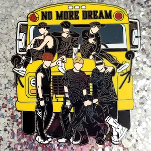 May include: A yellow enamel pin shaped like a school bus with the text NO MORE DREAM printed on the top. The design features seven stylized figures in black and white clothing posed in front of the bus, with red circular lights on the front.