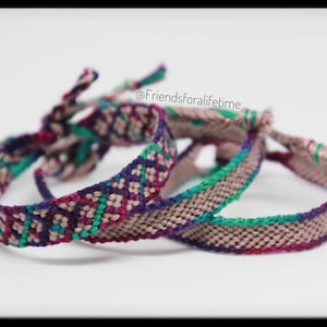 May include: Close-up of three friendship bracelets with woven patterns in shades of purple, teal, and pink. The bracelets are tied with matching threads. The text "@Friendsforalifetime" is visible.