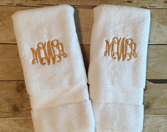 May include: Two white hand towels with gold embroidered initials "MEWA" on each towel.
