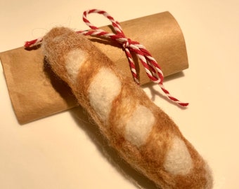 May include: A hand-felted brown and white baguette with a red and white twine bow tied around it.