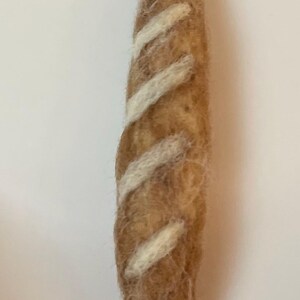 May include: A brown felt baguette with white felt stripes.