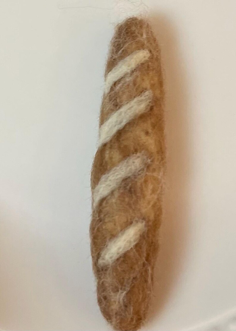 May include: A brown felt baguette with white felt stripes.