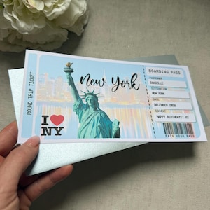 May include: A novelty boarding pass ticket for a trip to New York featuring an illustration of the Statue of Liberty, a skyline, and the text New York, I Love NY, Passenger Danielle, Destination New York, Date December 2026, and Happy Birthday XX.