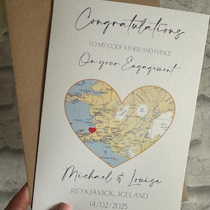 May include: An engagement card with the words "Congratulations" and "On your Engagement" in script. The card has a heart-shaped map of Iceland, with the names "Michael & Louise" and the date 14/02/2025. The card is inside a brown envelope.