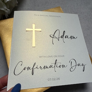 May include: A Confirmation Day card with a gold cross and the name "Adam" in script. The card reads "To a special grandson" and "With love on your Confirmation Day" with the date 07.02.26.