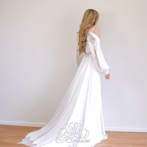 May include: A white satin bridal robe with a lace overlay and long sleeves. The robe has a flowing train and is perfect for a wedding day.