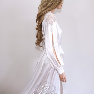May include: White satin robe with long sleeves and a lace overlay on the shoulders. The robe has a sash tie at the waist and a slit on each sleeve.