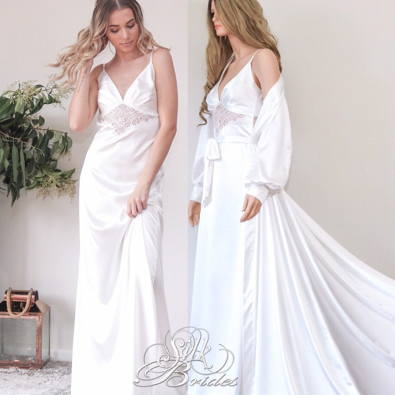 May include: Two white satin robes with lace detailing. One robe is a long, flowing gown with a V-neckline. The other robe is a shorter, more fitted style with a matching belt.