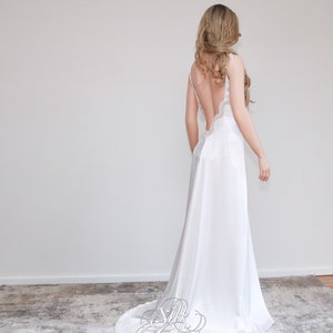 May include: A white silk slip dress with a low back and lace trim. The dress has a flowing skirt and is perfect for a special occasion.