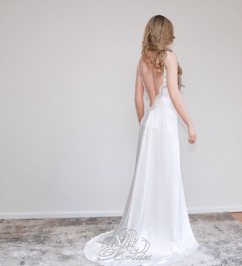 May include: A white silk slip dress with a low back and lace trim. The dress has a flowing skirt and is perfect for a special occasion.