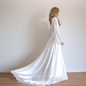 May include: A white satin robe with long, lace sleeves and a lace trim. The robe has a long train and is tied at the waist with a sash. The text "SILK BRIDES" is printed on the bottom of the robe.