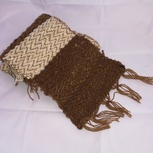May include: A brown and white woven scarf with fringe on the ends.