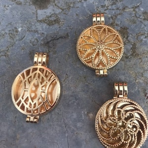 May include: Three gold-toned metal locket pendants with different openwork designs. The pendants are round and have a hinged opening.