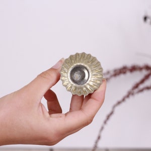 May include: A silver-colored metal cupcake mold with a fluted edge.