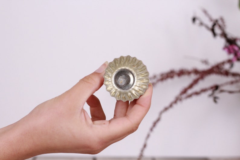 May include: A silver-colored metal cupcake mold with a fluted edge.