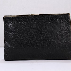 May include: A black leather clutch purse with a textured surface and a gold clasp.