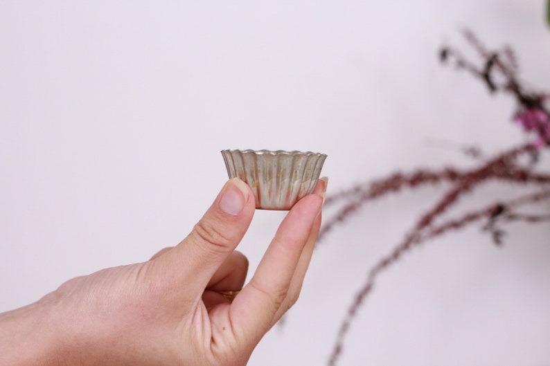 May include: A silver-colored metal cupcake pan with fluted edges.
