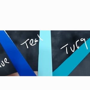 K&ouml;nnte beinhalten: Nahaufnahme von vier Stoffproben in verschiedenen Blaut&ouml;nen. Die Proben sind mit "Blue", "Teal" und "Turq" beschriftet.