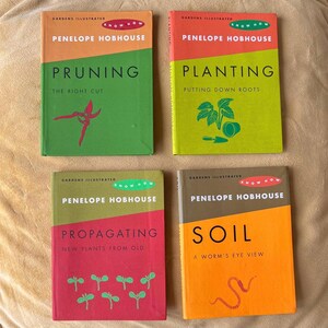 May include: Four vintage gardening books by Penelope Hobhouse. The books have colorful covers with titles like "Pruning," "Planting," "Propagating," and "Soil." Each book features a different color scheme, with text and illustrations related to gardening.