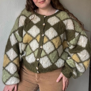 Puede incluir: Un cárdigan de punto con un patrón de rombos en tonos verdes, blancos y amarillos. El suéter con botones tiene un corte holgado y mangas largas. La prenda es una pieza cómoda y elegante, perfecta para combinar. Una adición acogedora a cualquier guardarropa.