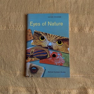 May include: A vintage book titled "Eyes of Nature" with a blue cover and colourful illustrations of animal eyes. The book is part of the National Audubon Society's Nature Program.