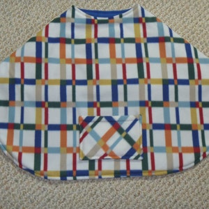 May include: A white fleece poncho with a blue, red, yellow, and green plaid pattern. The poncho has a small pocket on the front.