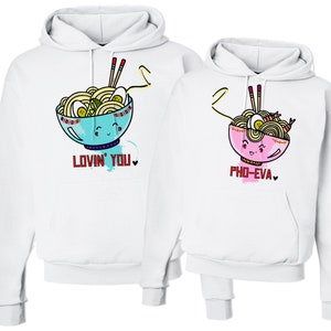 May include: Two white hooded sweatshirts with a cartoon noodle bowl design. One sweatshirt says "Lovin' You" and the other says "Pho-Eva".