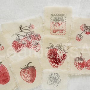 May include: A collection of fabric patches with red strawberry illustrations. Some patches feature whole strawberries, others show cross-sections, and some have text like "Strawberry Stamp 32¢". The designs are printed in red ink.