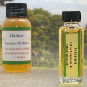 May include: Two small glass bottles of Datura essential oil blend. The bottles are clear and filled with a light yellow liquid. The labels are green and white with the text "Datura Essential Oil Blend" and "The Alchymist's Shell".
