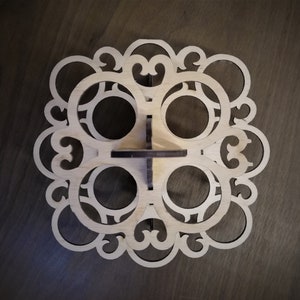 May include: A wooden cupcake stand with a decorative design. The stand has six circular cutouts for cupcakes and a central base.