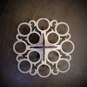 May include: A wooden egg holder with a decorative design. It has 12 circular cutouts for holding eggs.