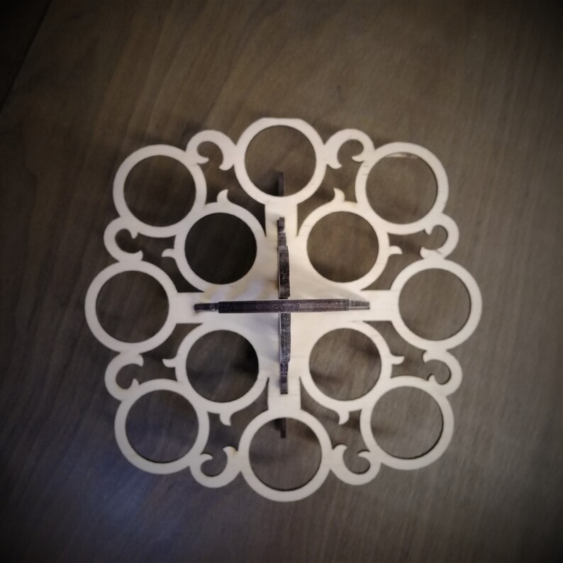 May include: A wooden egg holder with a decorative design. It has 12 circular cutouts for holding eggs.