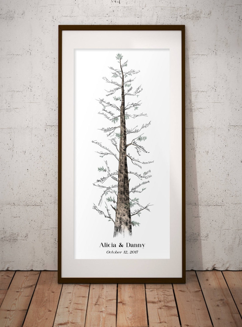 May include: A framed print of a hand-drawn tree with a brown trunk and green leaves. The tree is decorated with handwritten names and the text "Alicia & Danny October 12, 2017".